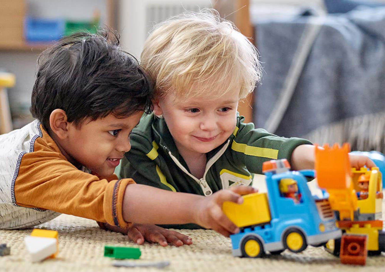 Two 4 year olds playing with a toy truck