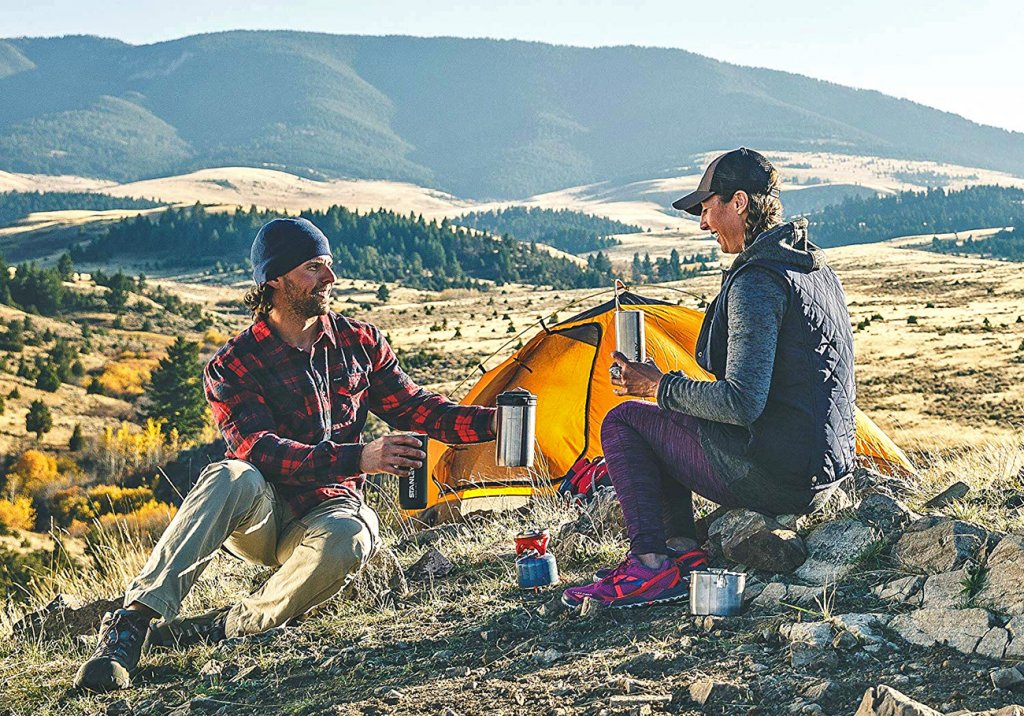 A couple using the Stanley Cook + Brew Camping Coffee Maker during a camping trip in the mountains