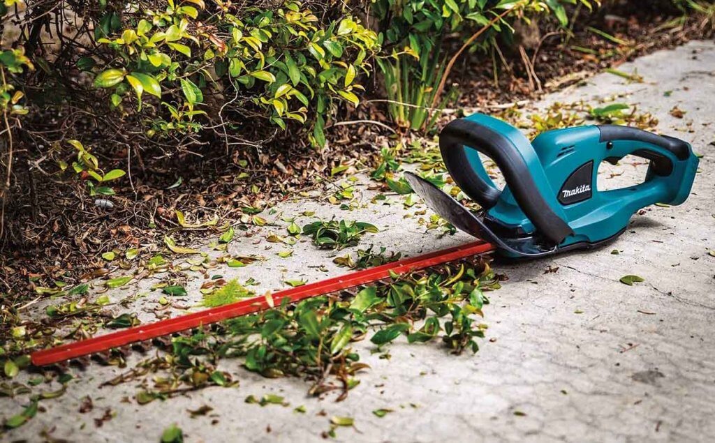 Makita XHU02Z Hedge Trimmer on the ground next to a hedge