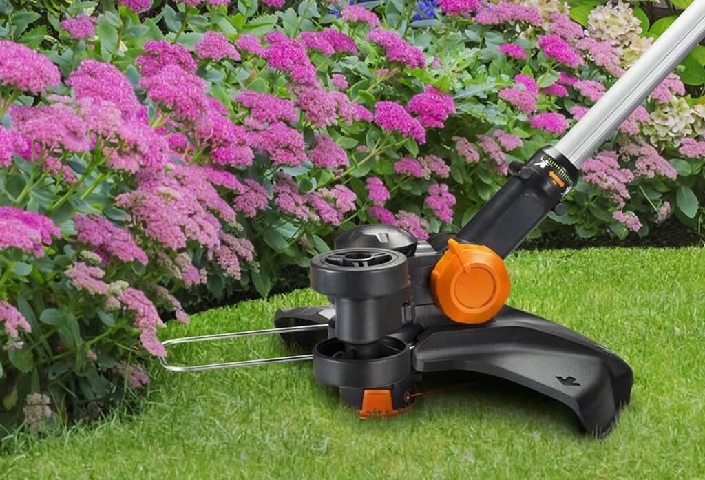 WORX WG170 GT Revolution 20V 12” cutting edge next to flowers
